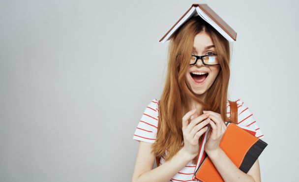 student smiling with a book on her head