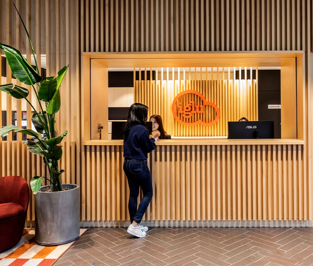 Student standing at front desk at Iglu Broadway, talking to customer service.