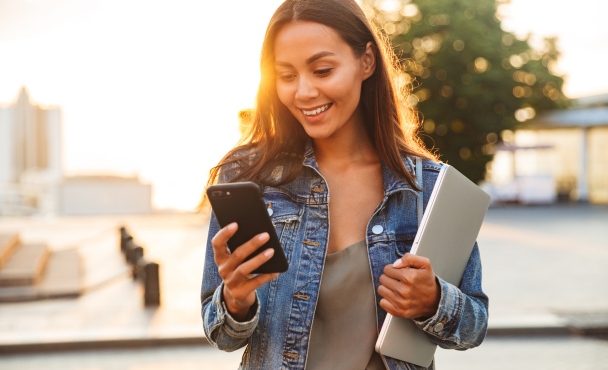 student-holding-laptop-and-using-smartphone